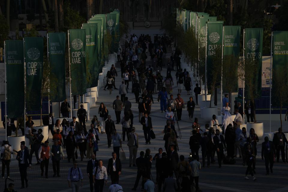 FILE - People walk through the COP28 U.N. Climate Summit as the sun sets, Dec. 2, 2023, in Dubai, United Arab Emirates. (AP Photo/Rafiq Maqbool, File)