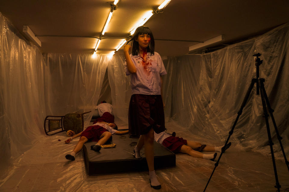 A final girl standing with blood on her face in a creepy, plastic covered room