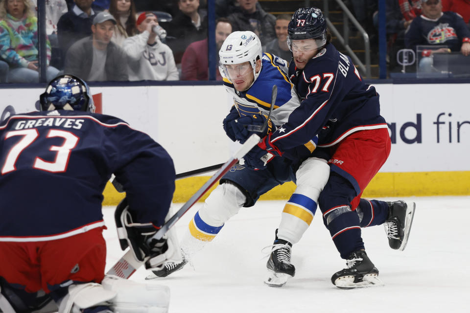 St. Louis Blues' Alexey Toropchenko, center, shoots the puck at Columbus Blue Jackets' Jet Greaves, left, as Nick Blankenburg defends during the first period of an NHL hockey game Friday, Dec. 8, 2023, in Columbus, Ohio. (AP Photo/Jay LaPrete)