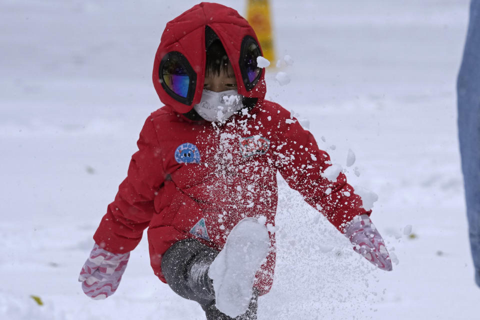A child kicks up fresh snow in Beijing, China, Sunday, Nov. 7, 2021. An early-season snowstorm has blanketed much of northern China including the capital Beijing, prompting road closures and flight cancellations. (AP Photo/Ng Han Guan)