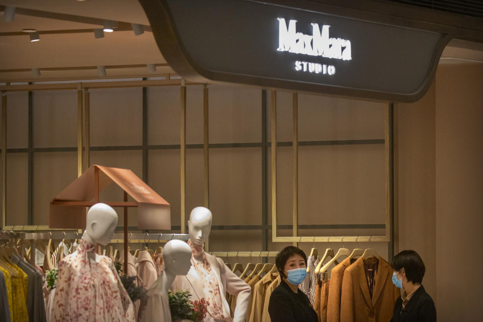 Employees stand at the entrance to a MaxMara clothing store at an upscale shopping mall in Beijing, Tuesday, March 16, 2021. Chinese state TV has criticized bathroom fixtures brand Kohler, automaker BMW and MaxMara fashion boutiques for using facial recognition to identify customers in a possible violation of privacy rules that took effect this year. (AP Photo/Mark Schiefelbein)