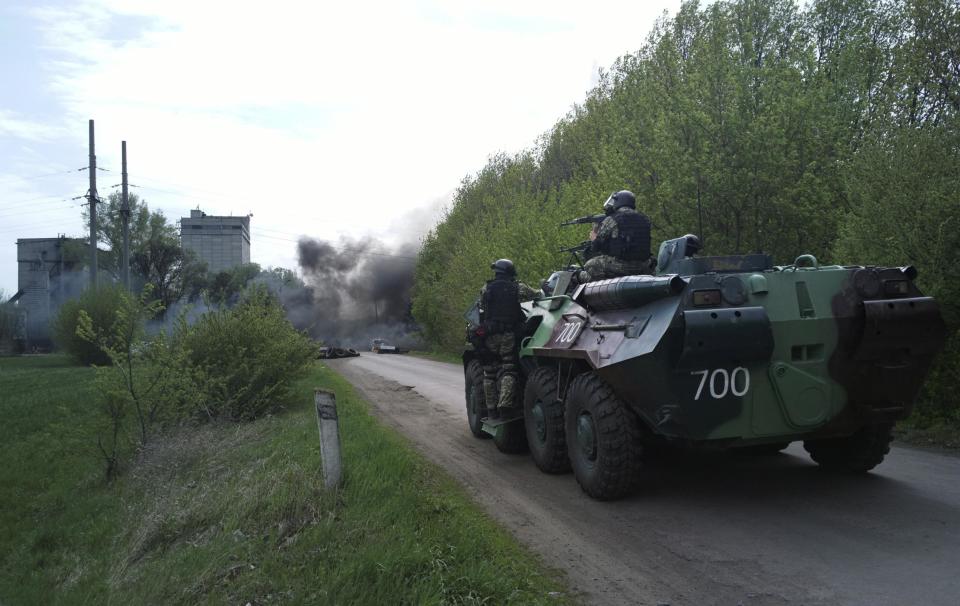 Ukrainian troops take position next to burning tires at a pro Russian checkpoint following an attack by Ukrainian troops outside in Slovyansk, Ukraine, Thursday, April 24, 2014. Ukrainian government troops moved against pro-Russia forces in the east of the country on Thursday and killed at least two of them in clashes at checkpoints manned by the insurgents, the government and insurgents said. Russian President Vladimir Putin decried what he described as a "punitive operation." (AP Photo/Mika Velikovskiy)