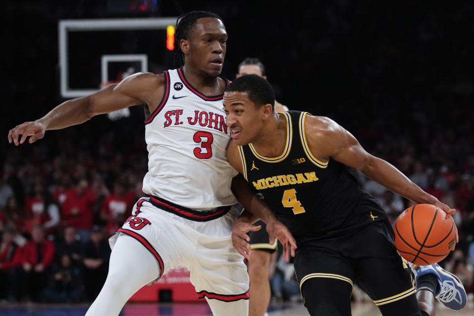 Michigan's Nimari Burnett (4) drives past St. John's Jordan Dingle (3) during the first half of an NCAA college basketball game Monday, Nov. 13, 2023, in New York. (AP Photo/Frank Franklin II)