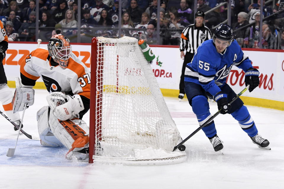 Winnipeg Jets' Mark Scheifele (55) skates around the net as Philadelphia Flyers' goaltender Brian Elliott (37) wayches him during second-period NHL hockey game action in Winnipeg, Manitoba, Sunday, Dec. 15, 2019. (Fred Greenslade/The Canadian Press via AP)