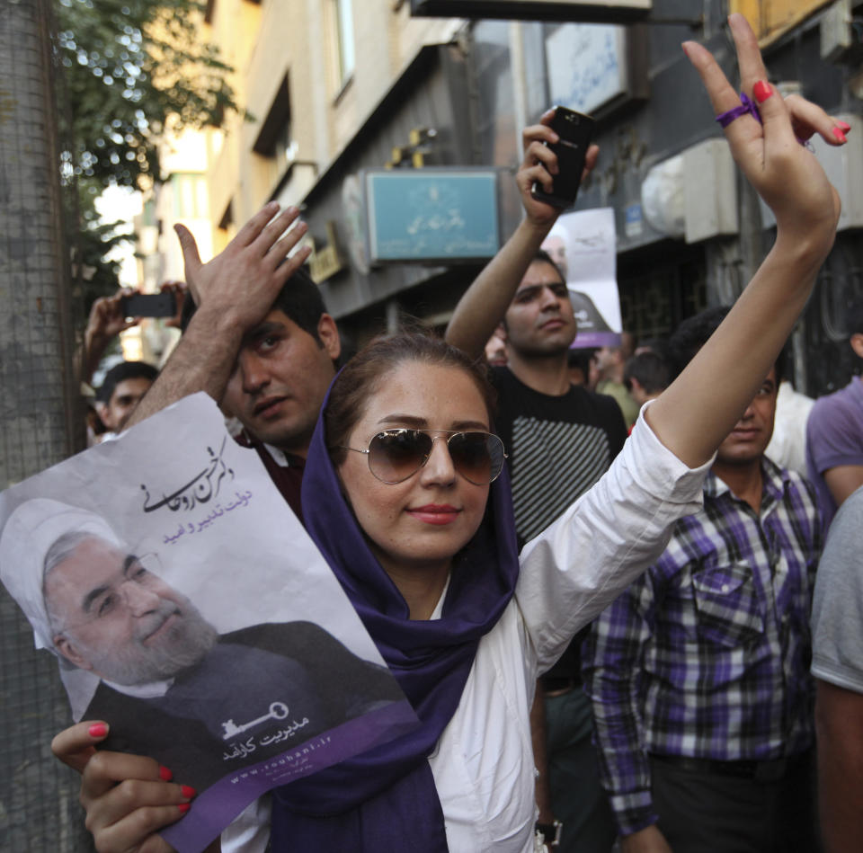 A female supporter of Iranian presidential candidate Hasan Rouhani flashes a victory sign, as she holds his poster, during a celebration gathering, in Tehran, Iran, Saturday, June 15, 2013. (AP Photo/Vahid Salemi)