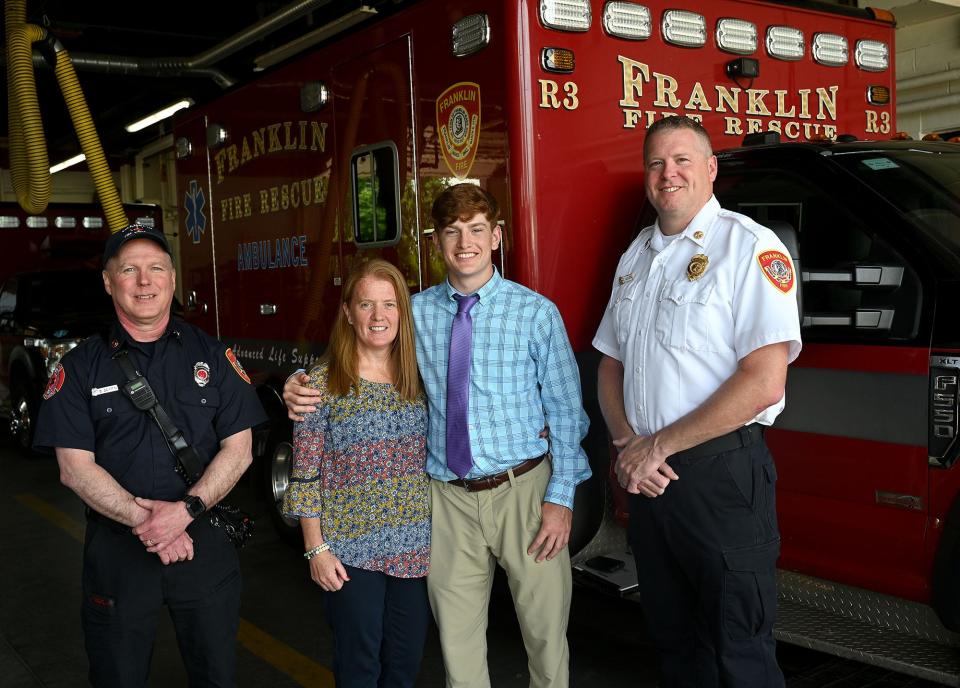Craig Scharland, 18, of Franklin, and his mother, Holly Scharland, pose with Franklin Fire Department Battalion Chief Chuck Allen, right, and Capt. Darrel Griffin at Franklin Fire Department headquarters, May 26, 2022. While en route to Milford Regional Medical Center on July 23, 2003, Allen and Griffin helped deliver Scharland on Route 140 in Hopedale. Scharland graduates from Bishop Feehan High School on June 3.