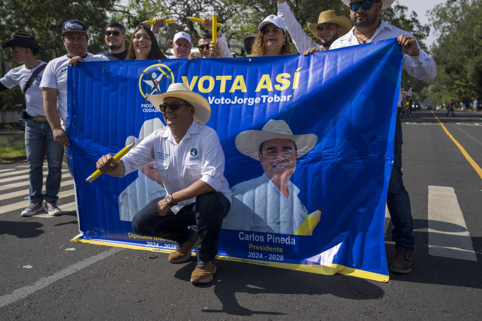 Supporters pose for photos with a banner of Carlos Pineda, presidential candidate of the Prosperidad Ciudadana party, prior to a campaign rally in Guatemala City, Sunday, May 14, 2023. Pineda has sent an “open letter” video to El Salvador´s President Nayib Bukele praising many of the president’s most controversial measures. “I have the goal of doing in Guatemala exactly what you are doing in El Salvador,” he said. (AP Photo/Moises Castillo)