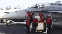 In this Monday, March 20, 2017 photograph, crew members work on an F-18 fighter jet abroad the USS George H.W. Bush as it travels toward the Strait of Hormuz. The arrival of the nuclear-powered aircraft carrier to the Persian Gulf marks the first such deployment under new U.S. President Donald Trump. (AP Photo/Jon Gambrell)