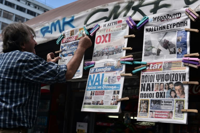 A man hangs newspapers bearing "No" and "Yes" headlines in central Athens, on July 4, 2015, on the eve of the Greek referendum on its bailout terms