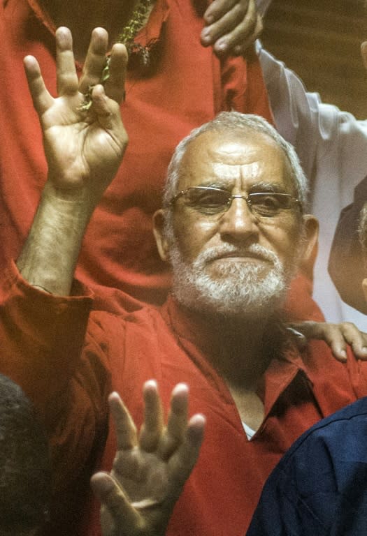 Egyptian Muslim Brotherhood leader Mohamed Badie (C) flashes the four finger symbol known as "Rabaa" from behind the defendant's cage as the judge reads out the verdict sentencing him and more than 100 other defendants on May 16, 2015