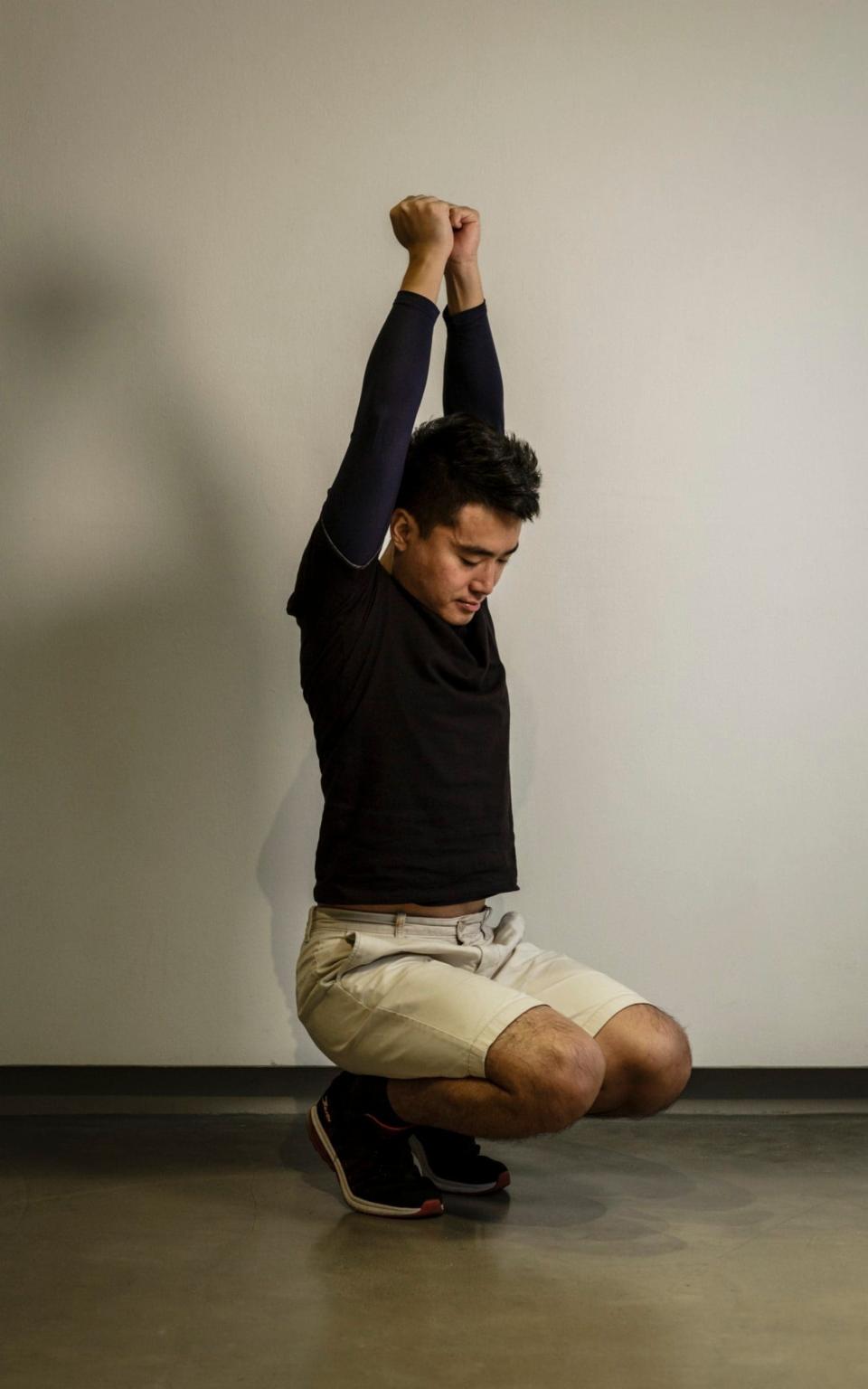 Simon Cheng demonstrates one of the positions security officers made his stand in for hours each day as part of his torture. If his muscles shook, he would be hit with a rod - OLIVIER MARCENY/OLIVIER MARCENY