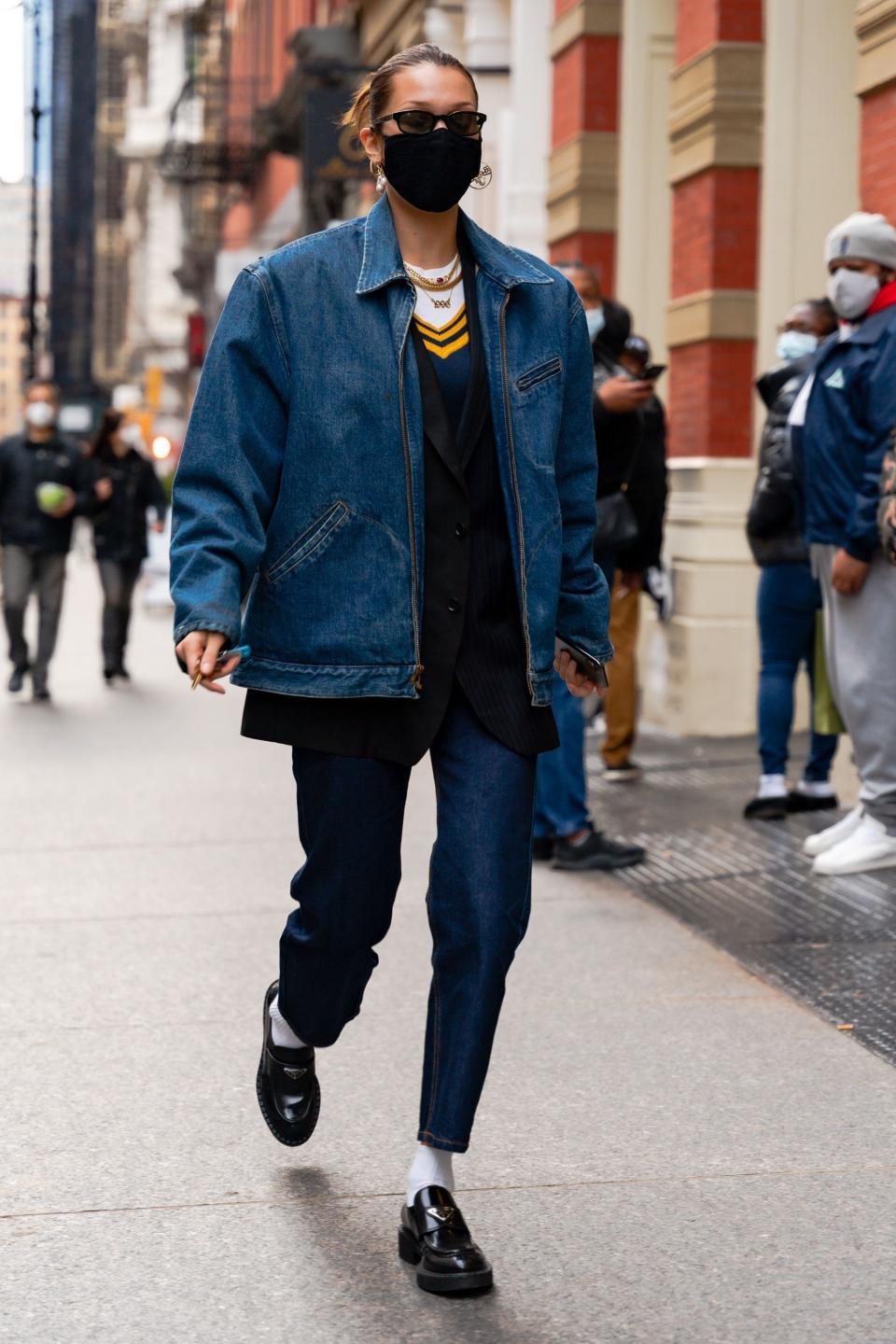 Bella Hadid in jeans, a sweater vest and an oversized jean jacket