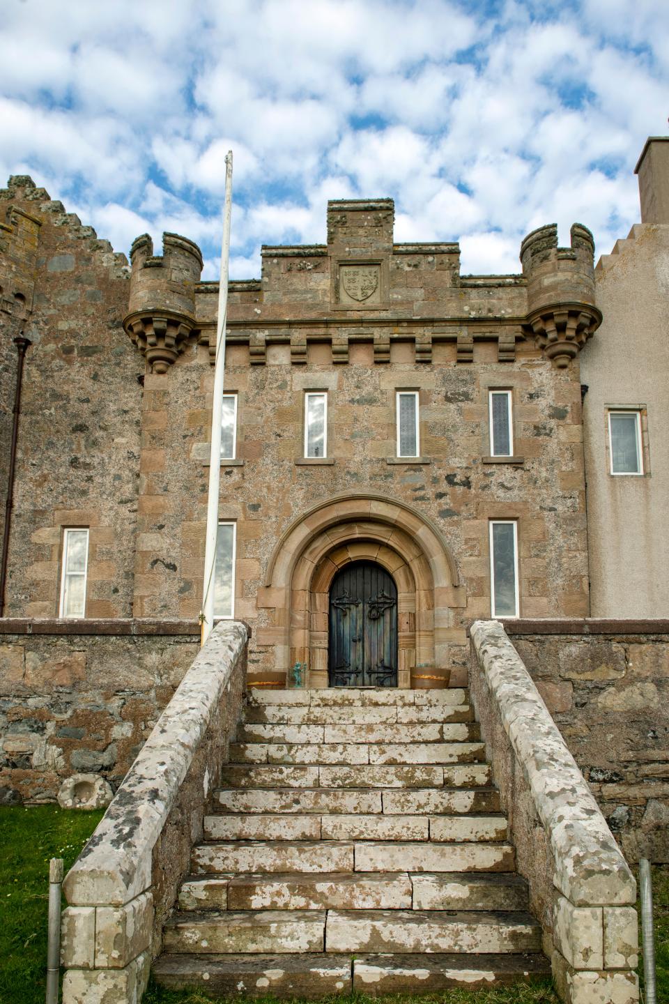 Stone steps lead up to the wooden doorway of the mansion.