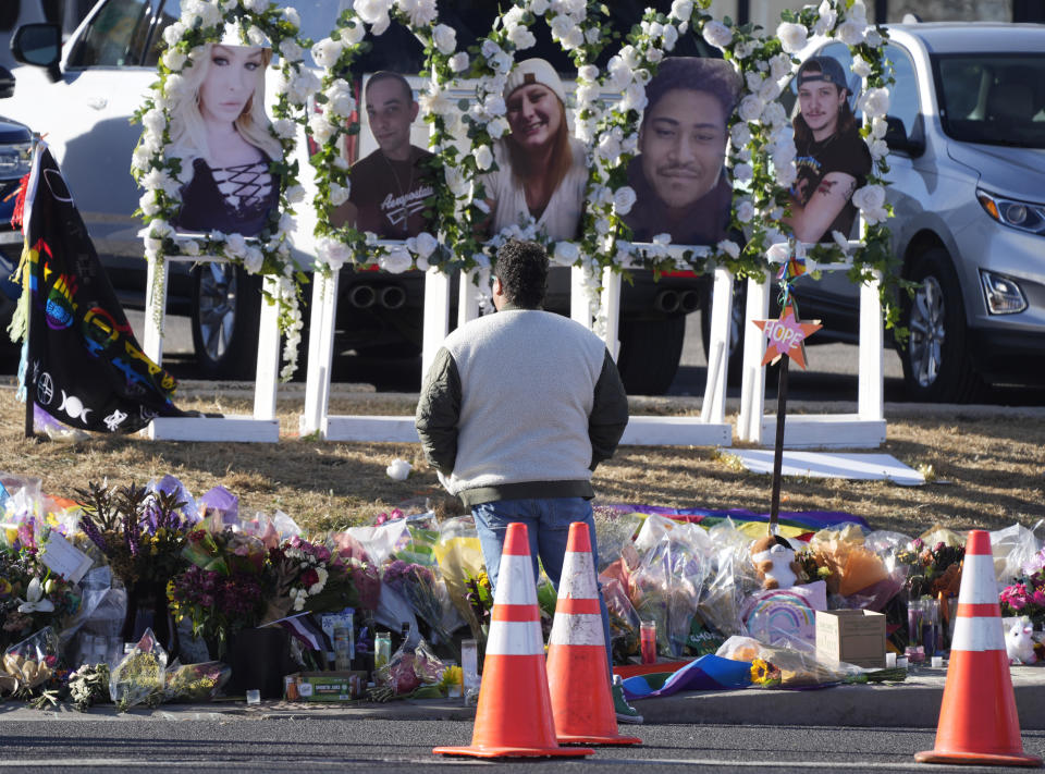 FILE - A person pauses to pay respects as portraits of the victims of a mass shooting at a gay nightclub are displayed at a makeshift memorial Nov. 22, 2022, near the scene in Colorado Springs, Colo. A court hearing is scheduled to start Wednesday, Feb. 22 ,for the 22-year-old suspect in the shooting. (AP Photo/David Zalubowski, File)