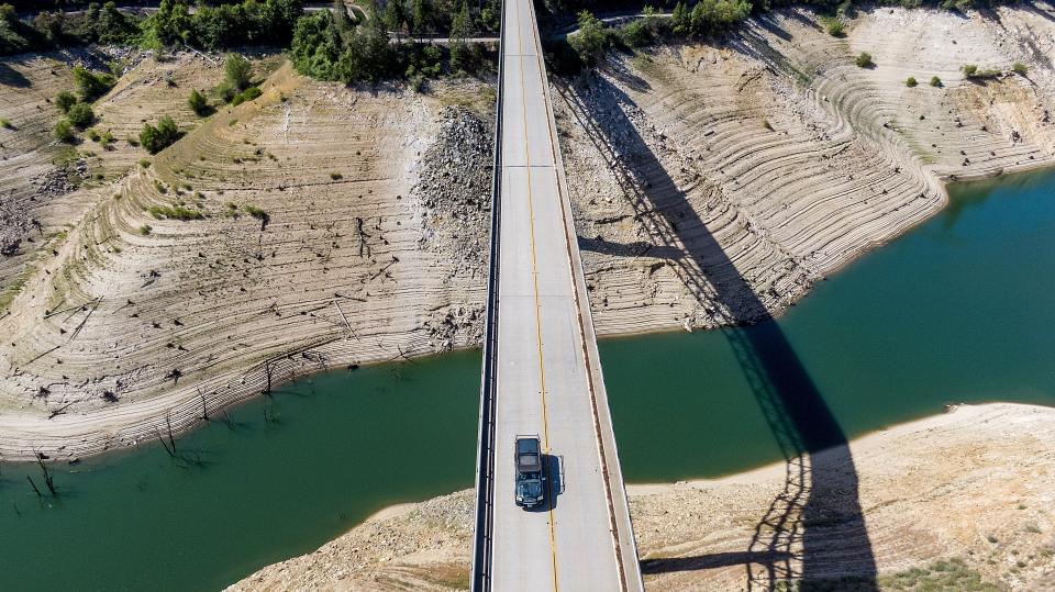 FILE - A car crosses Enterprise Bridge over Lake Oroville's dry banks on May 23, 2021, in Oroville, Calif. Months of winter storms have replenished California's key reservoirs after three years of punishing drought. (AP Photo/Noah Berger, File)