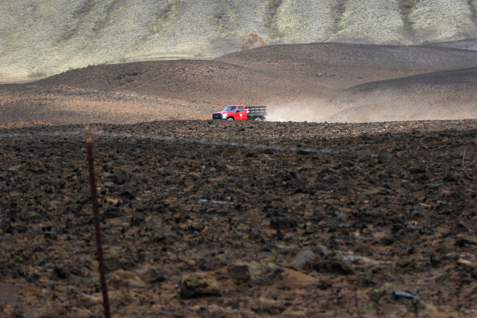 A fire official drives through a dry field after a wildfire on Thursday, Aug. 5, 2021, near Waimea, Hawaii. The area was scorched by the state's largest ever wildfire. (AP Photo/Caleb Jones)