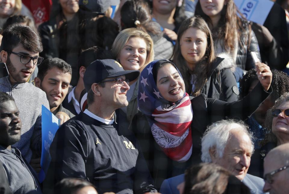 Michigan coach Jim Harbaugh takes pictures with fans following President Obama's rally for Hillary Clinton. (AP)