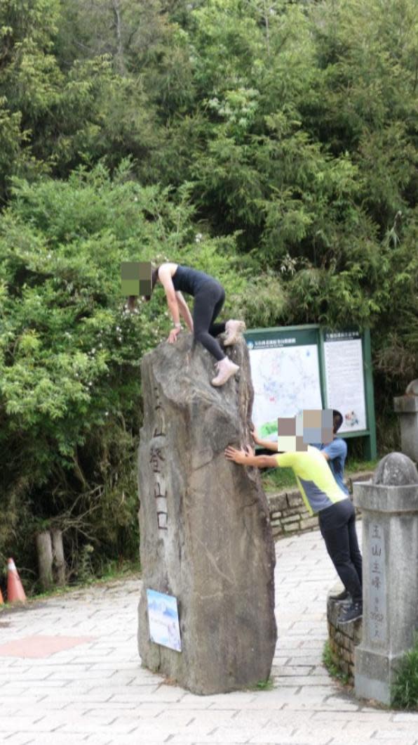 女子在男性友人的協助下攀爬石碑。（圖／翻攝自登山通報站臉書）