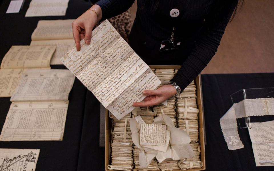A conservator displays undelivered letters sent from Lima to Cadiz in 1779 on the ship La Perla but seized the British, from The Spanish Prize Papers at a presentation event at The National Archives in London