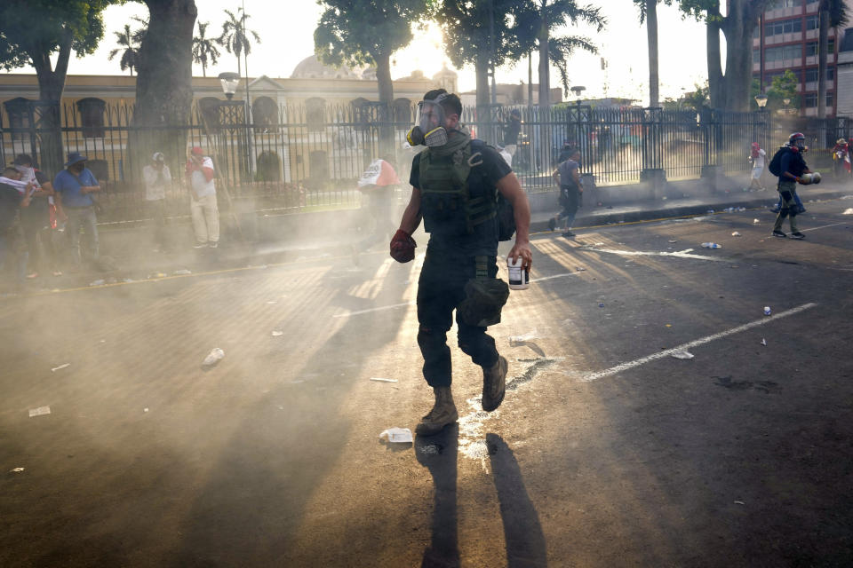 A so-called "deactivator" faces off against the police during one of the daily protests demanding the resignation of Peruvian President Dina Boluarte, in Lima, Peru, Thursday, Jan. 19, 2023. The protest movement's so-called "deactivators," volunteers donning gas masks, safety goggles and thick gloves, grab the hot tear gas canisters and toss them inside large plastic bottles filled with a mixture of water, baking soda and vinegar, a strategy to try to neutralize the effects of tear gas. (AP Photo/Martin Mejia)