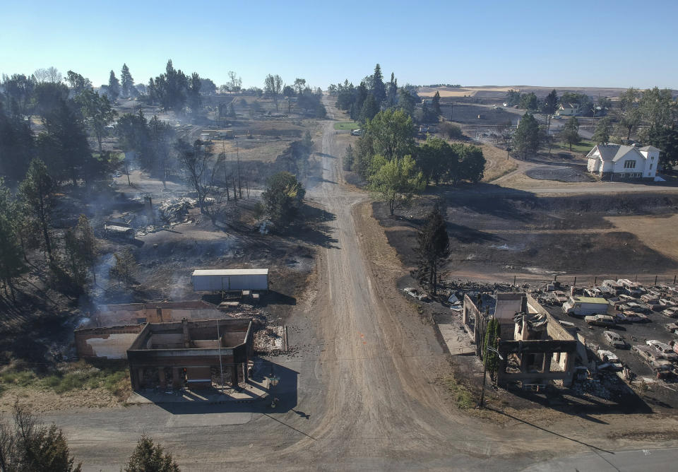 In downtown Malden, Washington, the former post office at lower left and another historic building at lower right still smolder Tuesday, a day after a fast-moving wildfire swept through the tiny town west of Rosalia. (Photo: Jesse Tinsley/The Spokesman-Review via Associated Press)