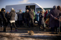 A cat sits in a patch of sunlight as villagers wait in line to receive humanitarian aid and register for a medical examination in a mobile clinic in the village of Blahodativka, Ukraine, Wednesday, Feb. 22, 2023. Volunteers for Alliance for Public Health, a Ukrainian health care organization, have set up a mobile treatment clinic that travels to recently liberated areas of eastern Ukraine. (AP Photo/Vadim Ghirda)