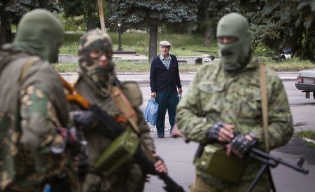 A man looks at armed pro-Russian separatists at a town center in Snizhnye in eastern Ukraine June 12, 2014. REUTERS/Shamil Zhumatov