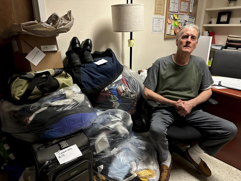 Scott Snyder sits among stored personal belongings for guests at an emergency shelter for homeless men run by St. Elizabeth Shelters in Santa Fe, N.M., on Monday, May 22, 2023. A new tally of the homeless population in New Mexico shows an abrupt jump in the number of people living without permanent housing or with no shelter at all amid surging prices for rent. (AP Photo/Morgan Lee)