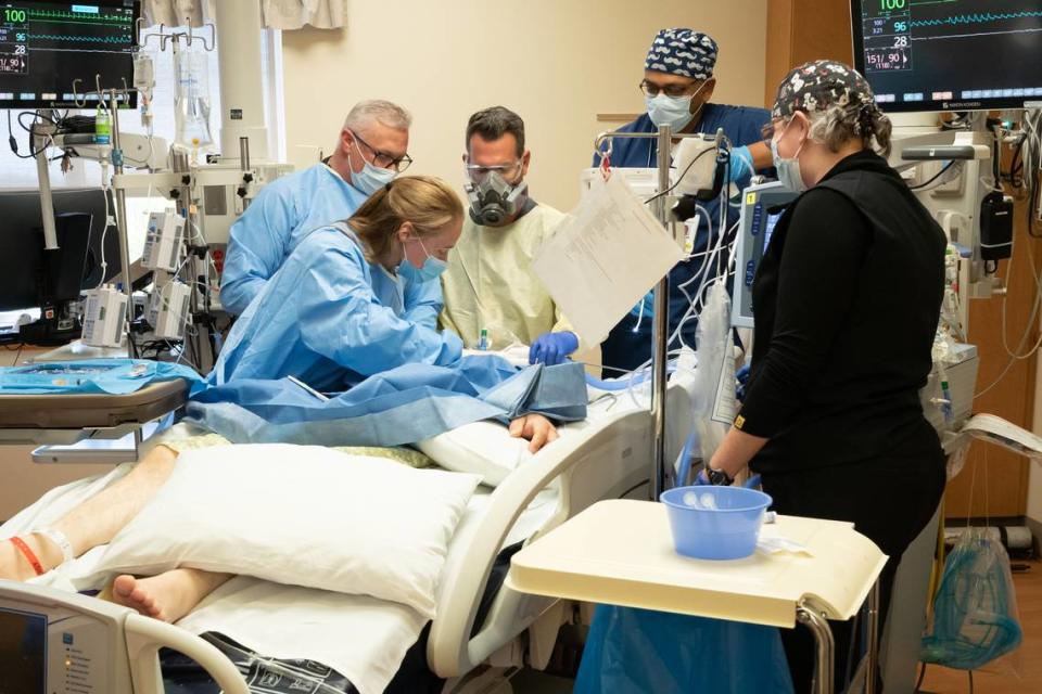 Health care workers in the ICU at Saint Alphonsus Regional Medical Center operate on a patient afflicted with COVID-19. This patient had been intubated with a breathing tube for two weeks, but continued to deteriorate. They have removed the endotracheal tube and are opening the trachea to insert a more permanent tube, a procedure called a tracheostomy.