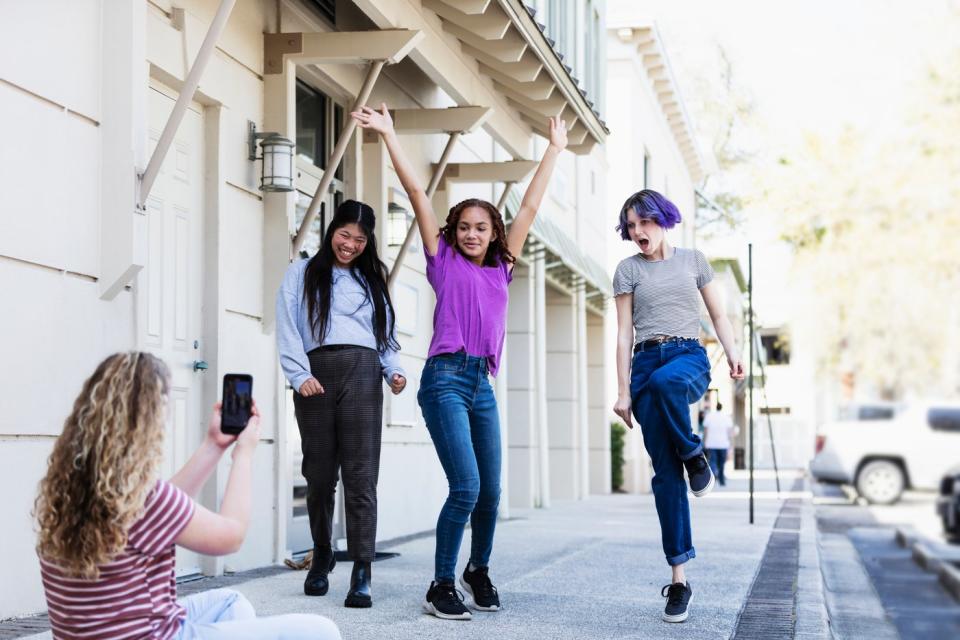 A person films three people dancing with a smartphone.