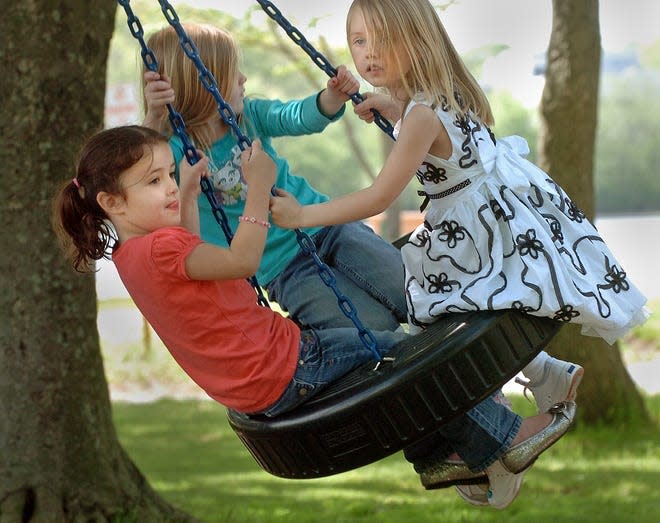 Three pre-schoolers enjoy the playground at Sunset Lake in Braintree on a warm afternoon.