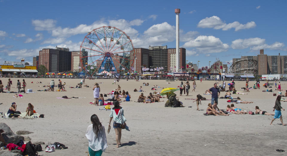 This June 12, 2013 photo shows the Wonder Wheel along the Coney Island boardwalk while visitors take to the beach in the Brooklyn borough of New York. (AP Photo/Bebeto Matthews)