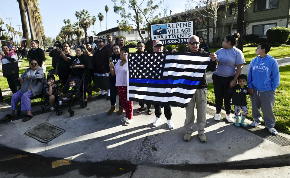 Residents line up in Riverside, Calif., to honor slain Riverside County Sheriff's deputy, Isaiah Cordero as the procession makes its way from the mortuary to the church for his funeral on Friday, Jan. 6, 2023. Cordero was shot and killed on Dec. 29, 2022, by a man with a violent criminal history during a traffic stop and the suspect later died in a shootout on a freeway, authorities said. (Watchara Phomicinda/The Orange County Register via AP)