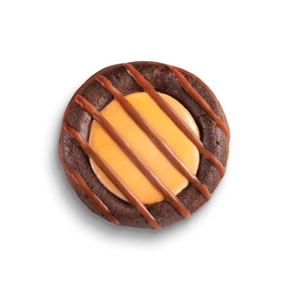 Promotional image of Adventurefuls close up, with a creamy-looking cararmel center, brownie-like cookie, and stripes of chocolate drizzled on top