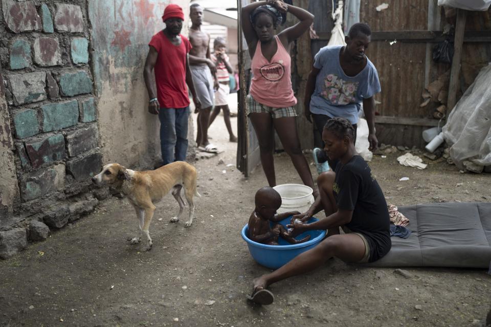 Una mujer desplazada por la violencia de las pandillas baña a su hijo en el patio de la casa de Jean-Kere Almicar, que ahora es un albergue improvisado, en Puerto Príncipe, Haití, el 2 de junio de 2023. Casi 200 antiguos residentes en la barriada humilde de Cite Soleil, próxima a la vivienda de Almicar, están acampados ahora en su propiedad y en las inmediaciones. Son parte de los cerca de 165.000 haitianos que huyeron de sus hogares ante el repunte de la violencia de las bandas. (AP Foto/Ariana Cubillos)