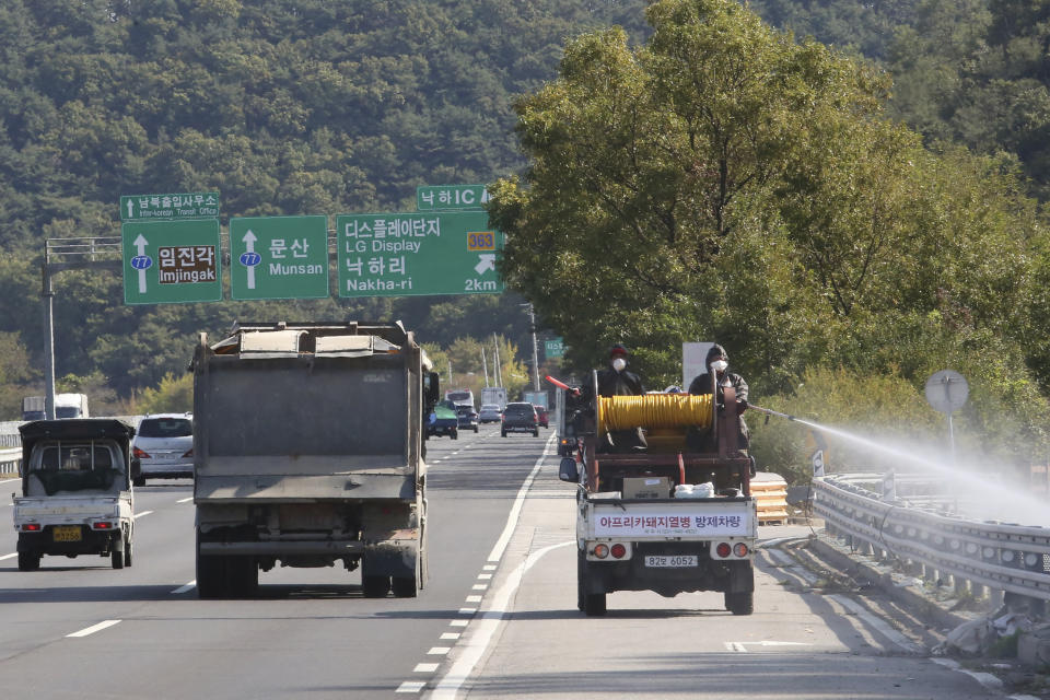 Disinfectant solution is sprayed from a vehicle as a precaution against African swine fever on the road in Paju, South Korea, near the border with North Korea, Tuesday, Oct. 15, 2019. Amid swine fever scare that grips both Koreas, South Korea is deploying snipers, installing traps and flying drones along the rivals' tense border to kill wild boars that some experts say may have spread the animal disease from north to south. (AP Photo/Ahn Young-joon)