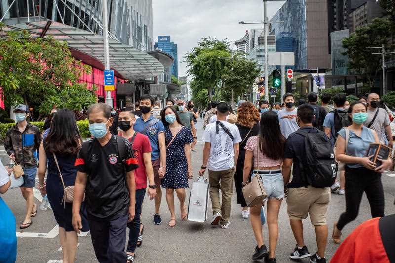 People wearing face masks as a preventive measure against the spread of covid-19 walk along Orchard Road, a famous shopping district in Singapore