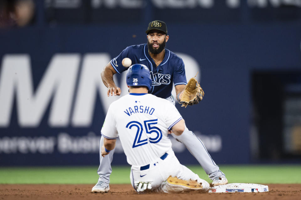 Toronto Blue Jays' Daulton Varsho (25) is hit on the head with a ball while advancing to second base as Tampa Bay Rays shortstop Amed Rosario, top, defends during the eighth inning of a baseball game in Toronto, Friday, May 17, 2024. (Christopher Katsarov/The Canadian Press via AP)