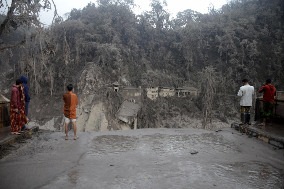 Villagers look at the broken bridge destroyed by the lava flow by the eruption of Mount Semeru in Lumajang district, East Java province, Indonesia, Sunday, Dec. 5, 2021. The death toll from the eruption of the highest volcano on Indonesia's most populous island of Java has risen by a score of still missing, officials said Sunday as rain continued to lash the area and hamper the search. (AP Photo/Hendra Permana)