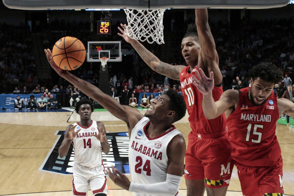 Alabama forward Brandon Miller (24) shoots a reverse layup around Maryland forward Julian Reese (10) and forward Patrick Emilien (15) in the first half of a second-round college basketball game in the NCAA Tournament in Birmingham, Ala., Saturday, March 18, 2023. (AP Photo/Butch Dill)