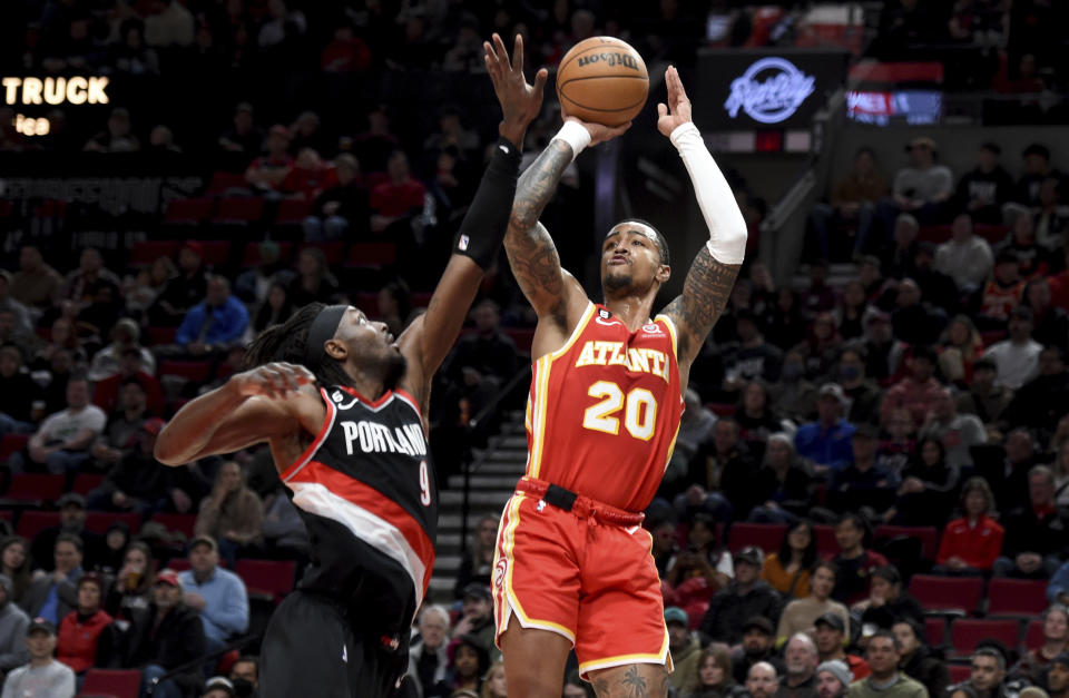 Atlanta Hawks forward John Collins, right, looks to shoot over Portland Trail Blazers forward Jerami Grant, left, during the first half of an NBA basketball game in Portland, Ore., Monday, Jan. 30, 2023. (AP Photo/Steve Dykes)