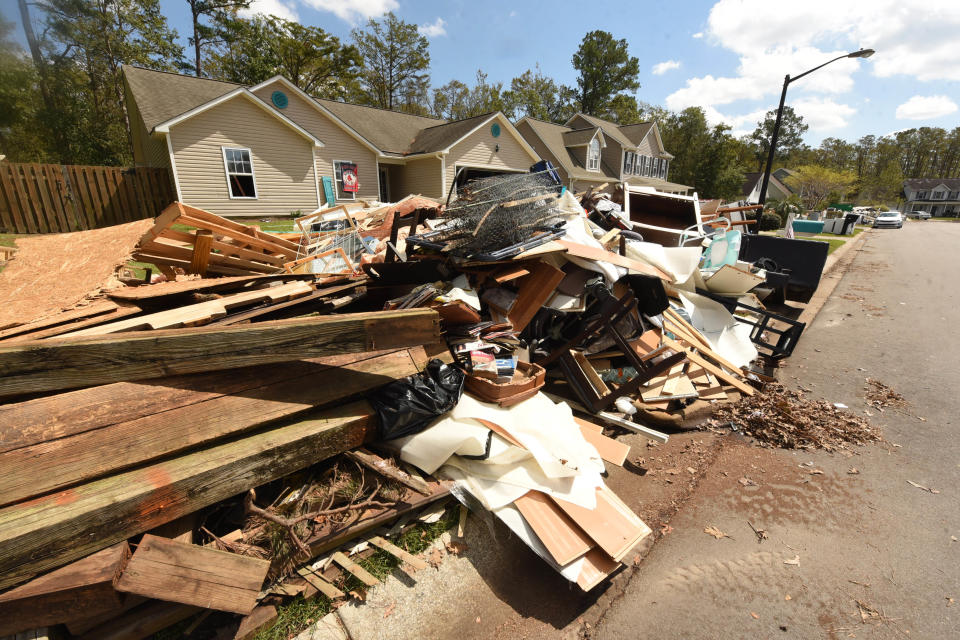 Debris litters yards in the Stoney Creek Plantation neighborhood Wednesday, Sept. 26, 2018, in Leland, N.C. Many of the homes here were flooded through their bottom floors due to rains from Hurricane Florence.