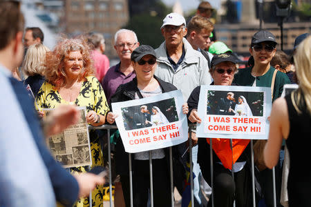 People hold posters of Britain's Prince Harry and wife Meghan, Duchess of Sussex in Sydney, Australia October 16, 2018. REUTERS/Phil Noble