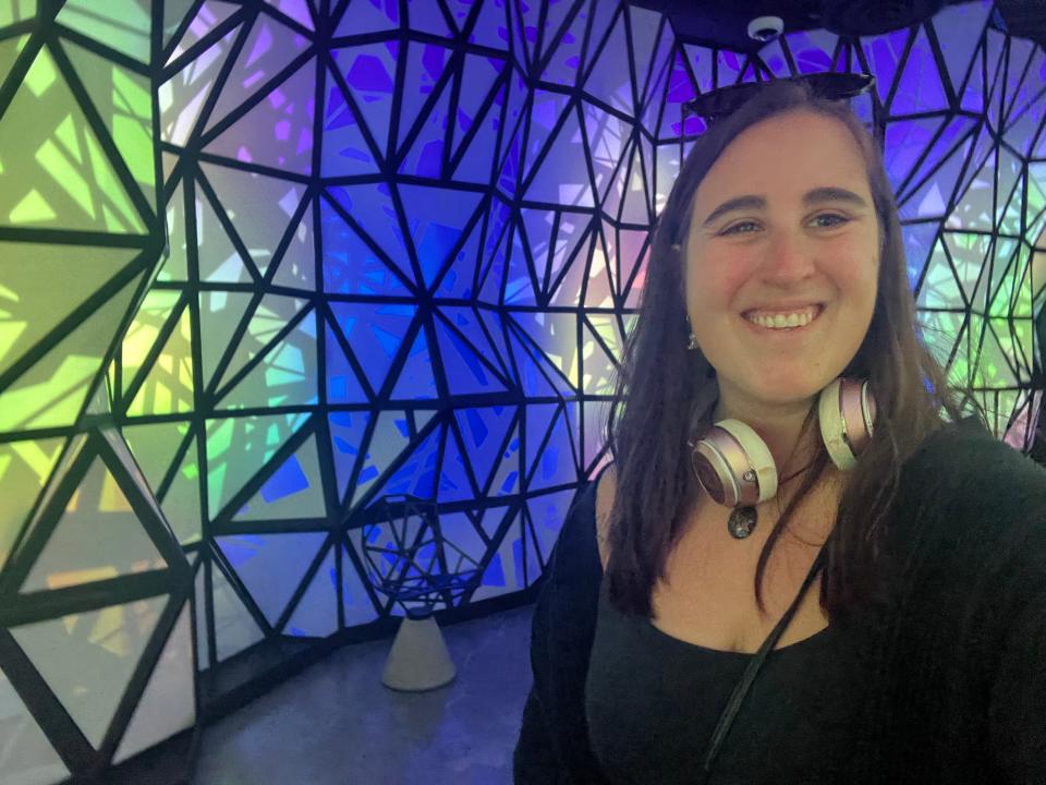 A selfie of the author with yellow and blue light walls behind her.