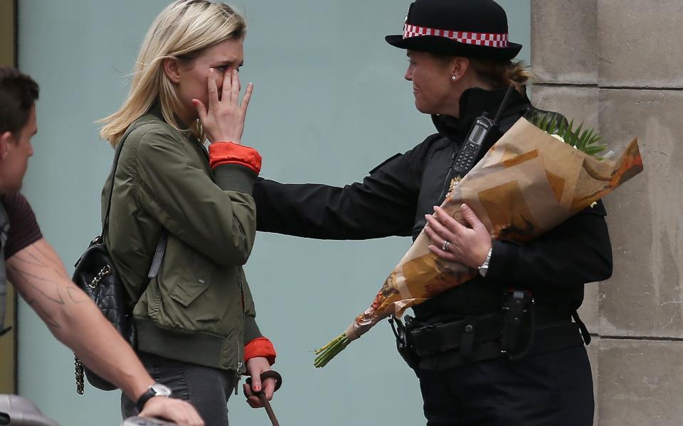 A woman reacts after asking a police officer to lay flowers near London Bridge - Credit:  DANIEL LEAL-OLIVAS