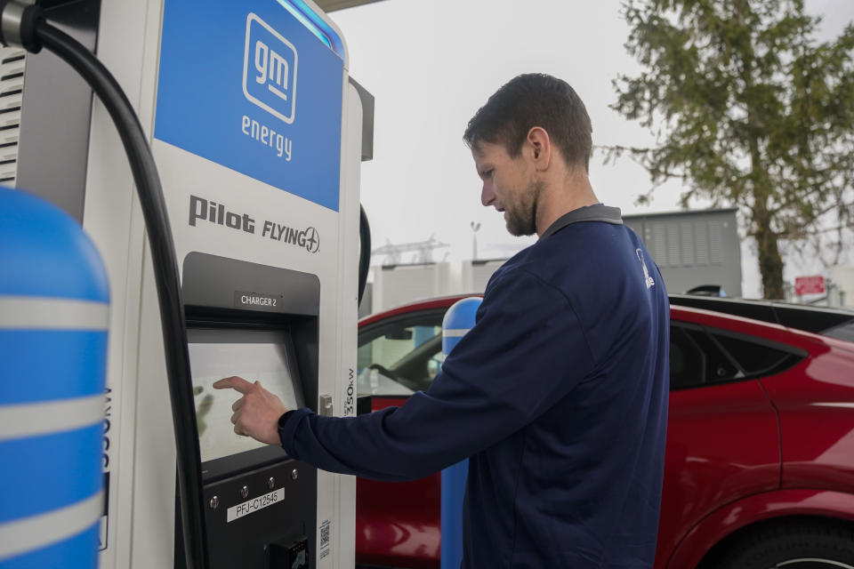 Liam Sawyer, of Indianapolis, touches the screen as he charges his 2023 Ford Mustang Mach-E, Friday, March 8, 2024, at an electric vehicle charging station in London, Ohio. The charging ports are a key part of President Joe Biden’s effort to encourage drivers to move away from gasoline-powered cars and trucks that contribute to global warming. (AP Photo/Joshua A. Bickel)