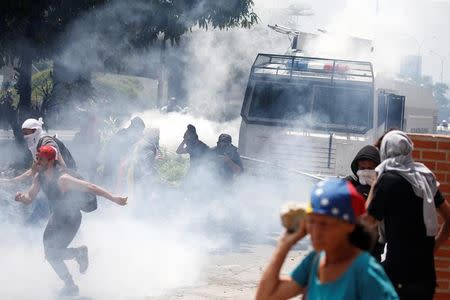 Manifestantes en medio del humo de las bombas lacricmógenas, mientras un carro lanza agua de la policía dispara para disolver una barricada durante una manifestación opositora en Caracas. 6 de abril de 2017. REUTERS/Carlos Garcia Rawlins