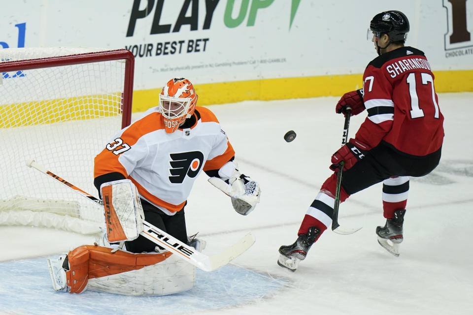 Philadelphia Flyers goaltender Brian Elliott (37) defends the net from New Jersey Devils' Yegor Sharangovich (17) during the first period of an NHL hockey game Tuesday, Jan. 26, 2021, in Newark, N.J. (AP Photo/Frank Franklin II)