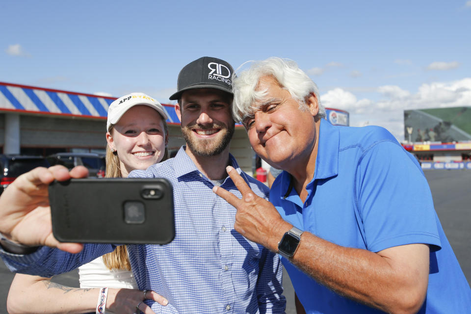 Entertainer Jay Leno smiles for a photo with fans at a NASCAR Cup Series auto race at Charlotte Motor Speedway in Concord, N.C., Sunday, May 30, 2021. Leno will be giving the command for drivers to start their engines. (AP Photo/Nell Redmond)