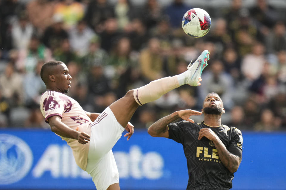 Portland Timbers defender Juan David Mosquera, left, kicks the ball as Los Angeles FC midfielder Kellyn Acosta watches during the first half of an MLS soccer match Saturday, March 4, 2023, in Los Angeles. (AP Photo/Jae C. Hong)